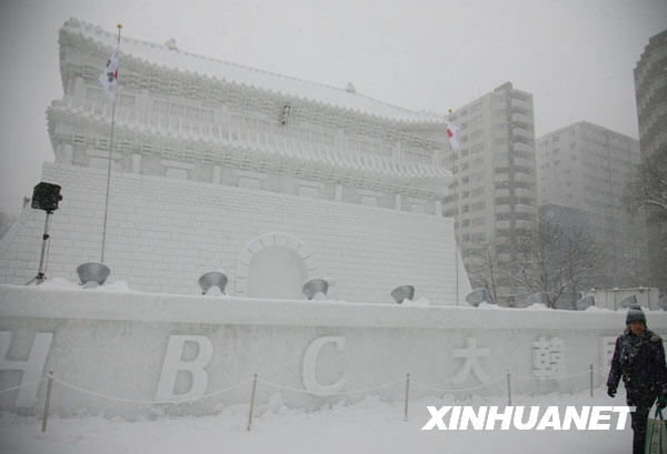 2月8日，在日本北海道札幌市舉行的第60屆札幌冰雪節上，游人從以韓國崇禮門為原型制作的雪雕旁走過。該雪雕長20米，寬27米，高15米。韓國崇禮門（亦稱南大門）是首爾歷史最悠久的建筑，1962年被韓國政府定為一號國寶。崇禮門在2008年2月發生的一場大火中被焚燒殆盡，計劃在2013年復原。